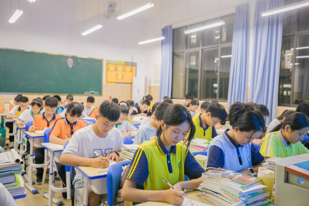 A group of students writing in a classroom during a lesson.